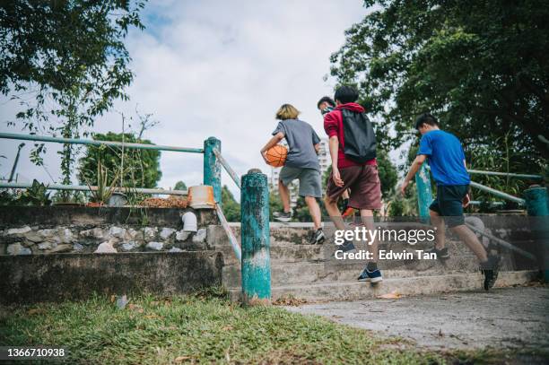 low angle view asian chinese teenage boy walking up staircase to basketball court for leisure friendly match during weekend - chinese teenage boy stockfoto's en -beelden