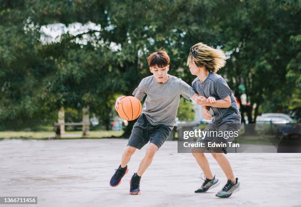 2 generation z asiatischer chinesischer teenager eins zu eins herausforderung beim basketballspielen am wochenende morgens beim basketballspielen - boy in hard hat stock-fotos und bilder