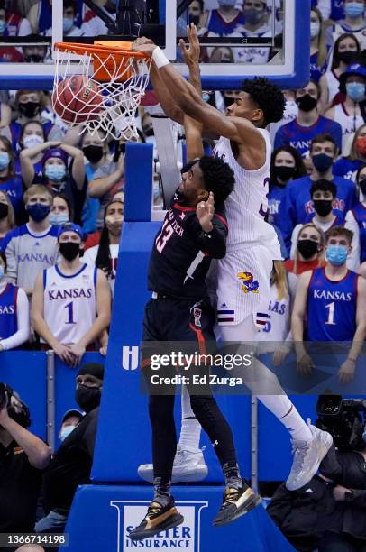 Ochai Agbaji of the Kansas Jayhawks dunks over Mylik Wilson of the Texas Tech Red Raiders during the second half at Allen Fieldhouse on January 24,...