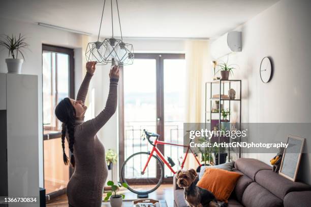 pregnant woman changing light bulbs. - installing ceiling light fixture stock pictures, royalty-free photos & images