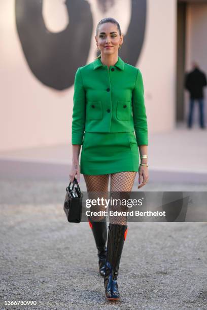 Chiara Ferragni wears gold chain earrings, a green jacket from Dior, matching green short skirt from Dior, gold bracelets, a black shiny leather Lady...