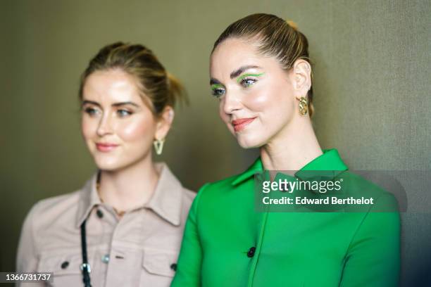 Valentina Ferragni wears gold and diamonds earrings, a gold large chain necklace, a beige denim jacket from Dior, a black shiny leather micro Vanity...