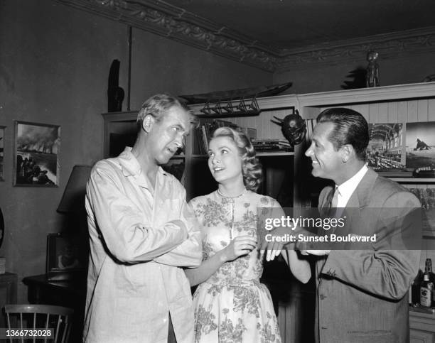 William Holden points out Grace Kelly's engagement ring to James Stewart in a moment of fun on the set of Hitchcock's 'Rear Window'.