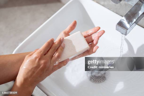 anonymous young woman washing her hands with soap and water at home - soap stockfoto's en -beelden