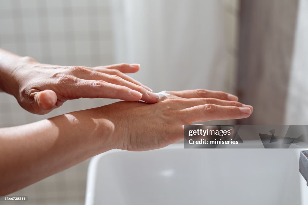 Anonymous Young Caucasian Woman Applying a Hand Cream in the Bathroom