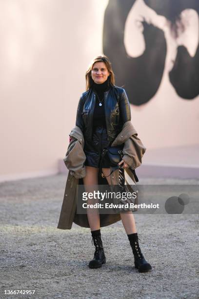 Eugénie Trochu wears a black wool turtleneck pullover, a black shiny leather jacket from Dior, matching black shiny leather buttoned short skirt from...