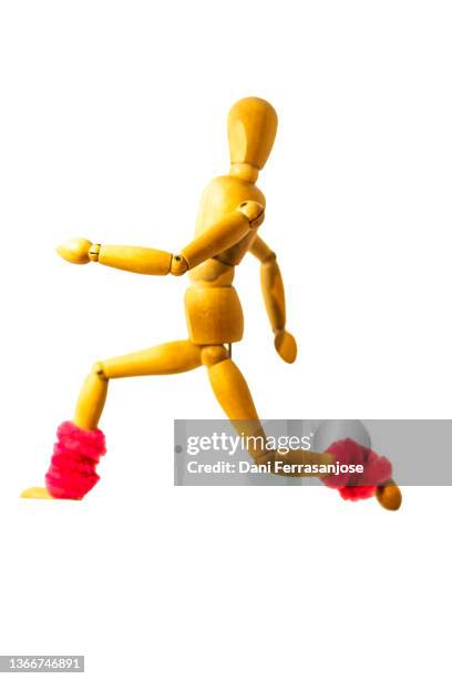 wooden doll with ankle warmers simulating the concept of running with a white background - maniquí fotografías e imágenes de stock