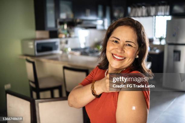 portrait of a happy mature latin woman showing arm after vaccination - vaccine confidence stock pictures, royalty-free photos & images