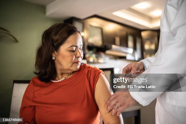 mature latin woman being vaccinated at home - immunology stock pictures, royalty-free photos & images