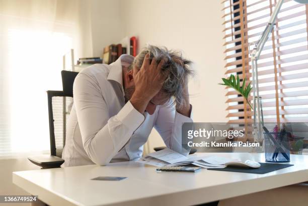 financial problems, depressed senior man checking bills and worried about about debt or financial crisis. - crisis response stock pictures, royalty-free photos & images