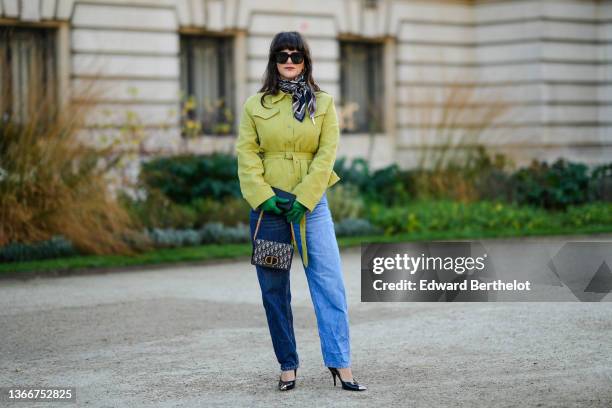 Gili Biegun wears sunglasses, navy blue / burgundy / white Dior Oblique Jacquard print pattern silk scarf from Dior, a green belted ruffled jacket, a...