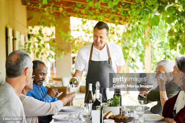 sommelier pouring wine for men and women at porch - sommelier stock pictures, royalty-free photos & images