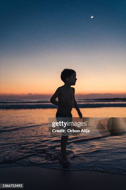 boys playing at the beach during sunset - child silhouette ocean stock pictures, royalty-free photos & images