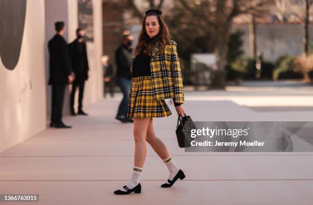 Cleo von Adelsheim is wearing a yellow and black skirt and blazer, a black turtleneck pullover, a black handbag and white Dior socks in black Dior...