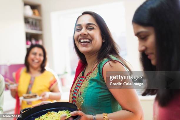 happy indian woman in sari preparing food with family in kitchen - woman cooking stock pictures, royalty-free photos & images