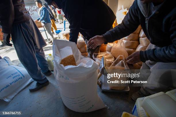 Lentils are weighed out as Afghans collect a monthly ration of staple food - flour, lentils, oil and salt - to stave off impending famine from a UN...