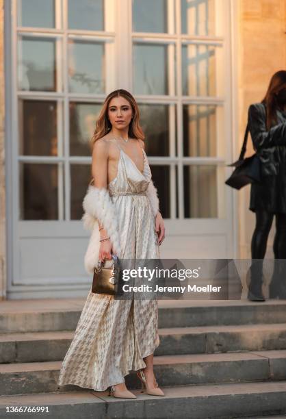 Zerrouki wears diamond earrings, a silver chain with heart diamond pendant necklace, a beige and silver emrboidered houndstooth print pattern V-neck...