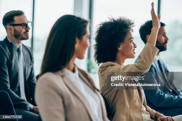 une femme d’affaires veut poser une question lors d’un séminaire. - mains en l'air photos et images de collection