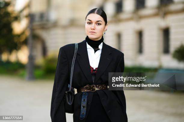 Guest wears gold earrings, a black turtleneck pullover, a gold chain necklace, a white shirt, a black oversized blazer jacket, a black high waist...