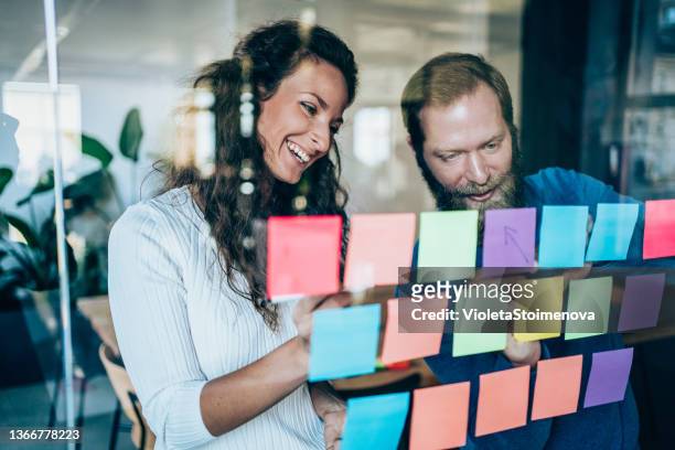 geschäftsleute brainstormen mit klebenotizen in einem meeting - company culture stock-fotos und bilder