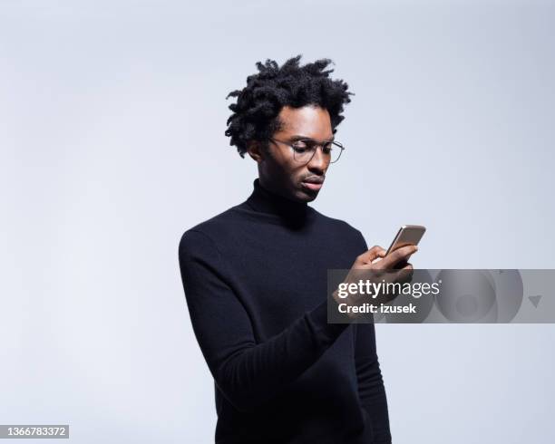 young man in black turtleneck using smart phone - black turtleneck stock pictures, royalty-free photos & images