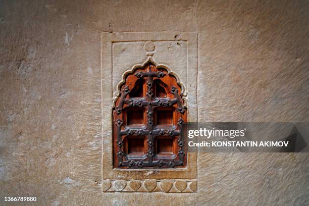 Small wooden decorative window in a stone wall. Oriental vintage style