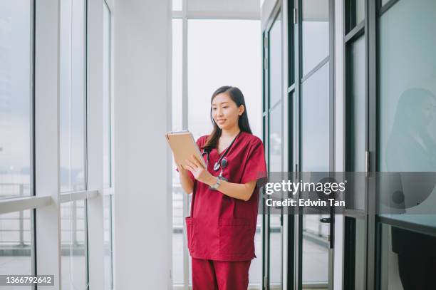 enfermera china enfermera de atención médica sonriendo mirando el portapapeles en el informe de salud del paciente en el pasillo del hospital - vestimenta de hospital fotografías e imágenes de stock