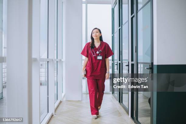 asian chinese female nurse smiling walking at corridor of hospital - nurse full length stock pictures, royalty-free photos & images