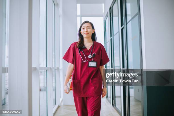 asian chinese female nurse smiling walking at corridor of hospital - nurse walking stock pictures, royalty-free photos & images