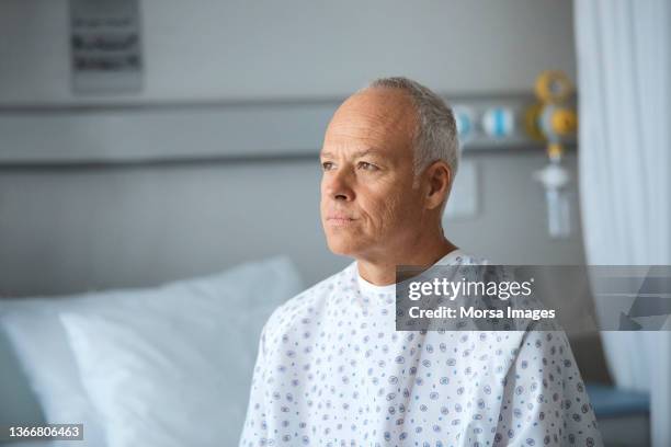 thoughtful male patient in hospital ward - adult male hospital bed stock-fotos und bilder