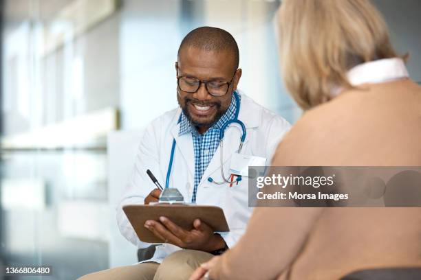 doctor discussing with patient in hospital - huisarts stockfoto's en -beelden