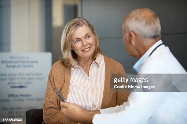 senior woman listening to male doctor in hospital - doctor and patient talking fotografías e imágenes de stock