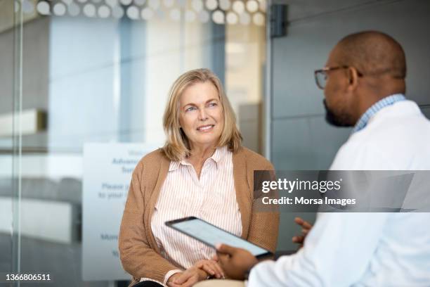 senior woman listening to doctor in hospital - docter stock-fotos und bilder