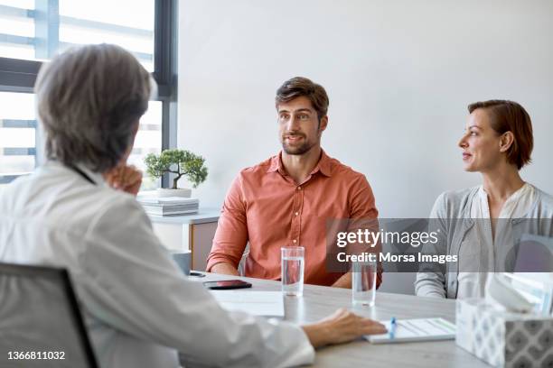 couple discussing with doctor in clinic - older woman younger man - fotografias e filmes do acervo