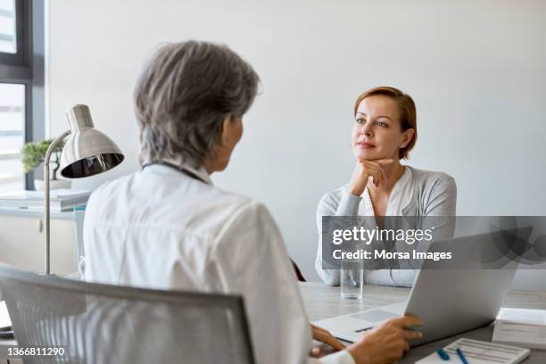 doctor discussing with patient in clinic - woman talking doctor stock-fotos und bilder