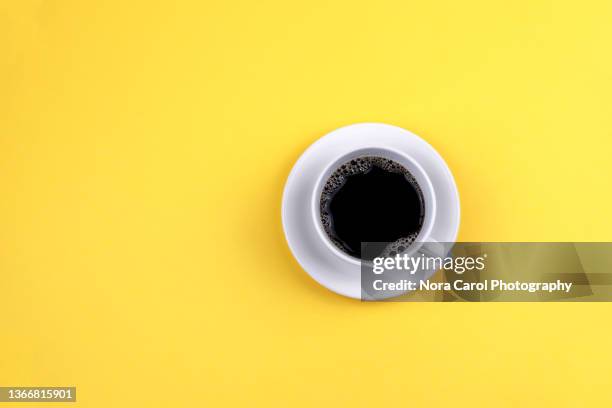 coffee cup with saucer on yellow background - black cup saucer stock pictures, royalty-free photos & images