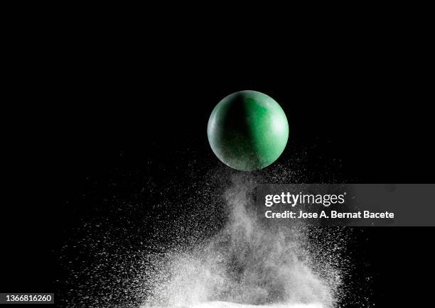 impact and rebound of a toy ball on a surface of land and powder on a black background - ballon rebond stock-fotos und bilder