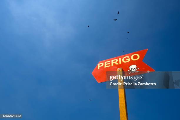 red plate with warning of "danger" against sky. perigo (in portuguese language). - perigo 個照片及圖片檔