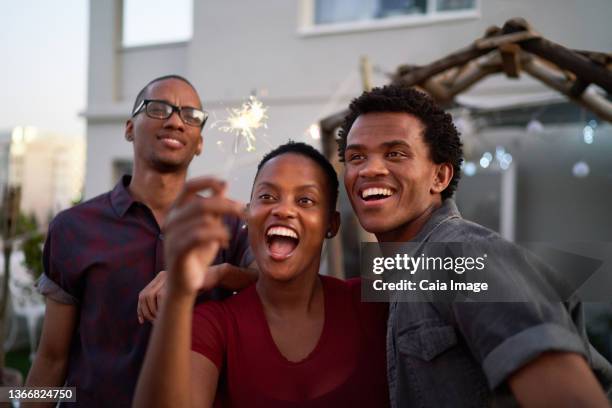 happy young friends with sparkler on patio - caiaimage stock-fotos und bilder