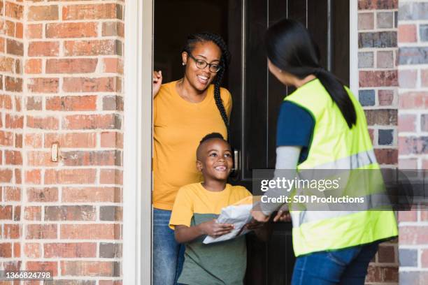 elementary age boy happily receives packages from mail person - postbode stockfoto's en -beelden