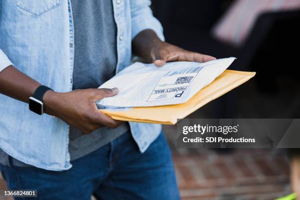 standing on front porch, unrecognizable man receives packages - postbode stockfoto's en -beelden