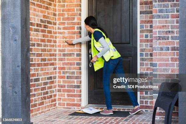 après avoir laissé des enveloppes sur le tapis, le livreur sonne à la porte - ringing doorbell photos et images de collection