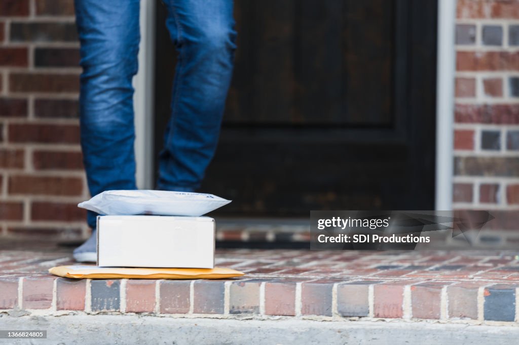 Unrecognizable male homeowner approaches packages left on doorstep