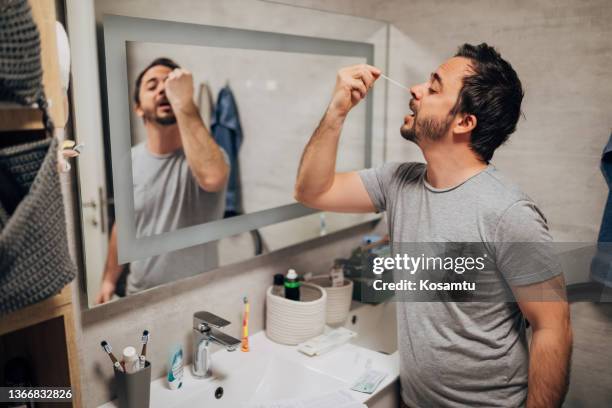 man doing nasal swab to check coronavirus infection, after the first symptoms of coronavirus. - cotton swab stock pictures, royalty-free photos & images