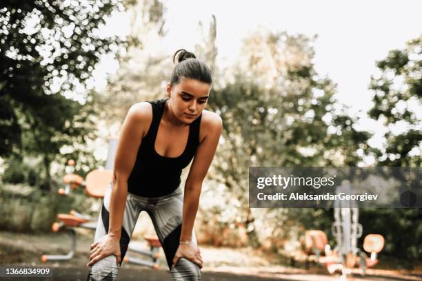 beautiful female athlete taking breath after exercising - hand on knee stock pictures, royalty-free photos & images