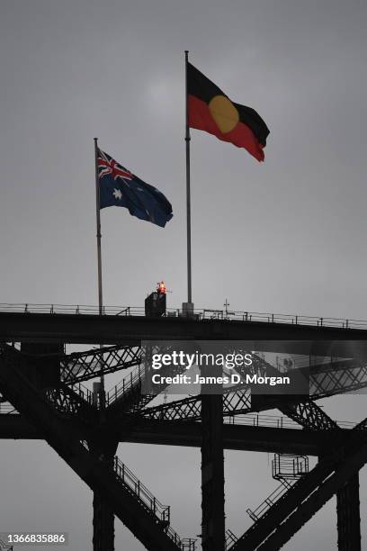 The Aboriginal flag is raised alongside the Australian flag atop the Sydney Harbour Bridge at sunrise on January 26, 2022 in Sydney, Australia....