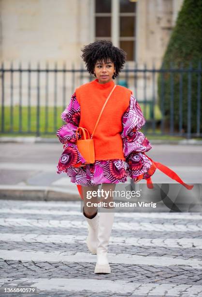 Guest is seen wearing orange slipover, dress, boots, bag outside Chanel during Paris Fashion Week - Haute Couture Spring/Summer 2022 on January 25,...