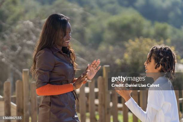 monoparental family with mixed race child outdoor playing - monoparental stock-fotos und bilder