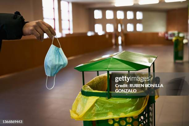 midsection of caucasian man throwing used surgical mask into the trash bin in a corridor. healthecare concept. - end stock-fotos und bilder