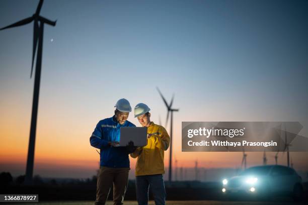 young maintenance engineer team working in wind turbine farm at sunset - it technician foto e immagini stock